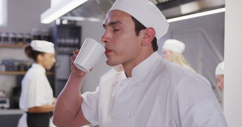 Meditative Male Chef Savoring Coffee Break in Bustling Kitchen