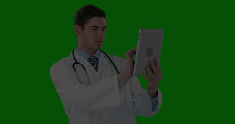 Doctor holding tablet and studying electronic records on green screen for telemedicine
