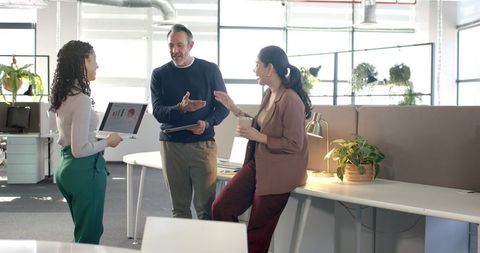 Diverse team discussing presentation in modern sunlit open-plan office