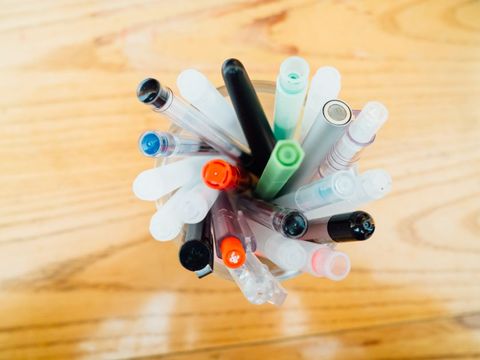 Colorful Variety of Pens in Cup on Wooden Surface