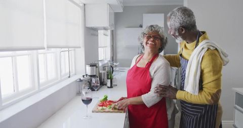 Senior Couple Sharing Joyful Cooking Moments in Modern Kitchen