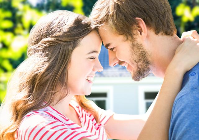 Romantic young couple smiling and embracing outdoors, conveying love and happiness. Ideal for use in relationship-focused articles, romance novel covers, or social media posts about love and togetherness.