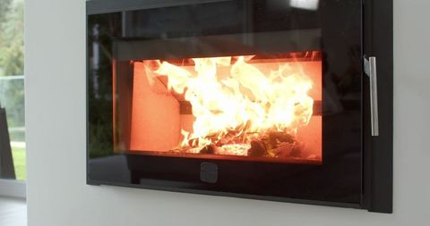 Modern wall-mounted wood-burning fireplace glowing with warm flames and embers