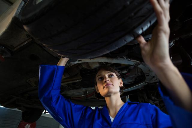 Female mechanic examining a car wheel in repair garage