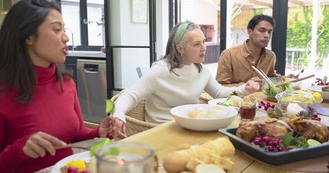 Multigenerational family enjoying homemade roast dinner at cozy dining table