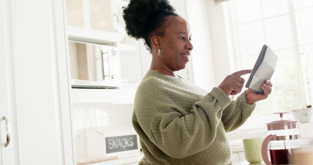 Mature African American Woman Using Tablet in Bright Kitchen - Download Free Stock Images Pikwizard.com