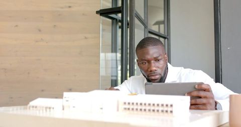 Architect analyzing building model using tablet in office