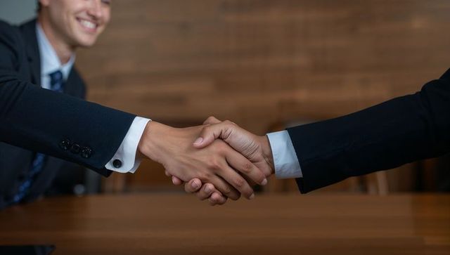 Business partners shaking hands over wooden table sealing corporate agreement