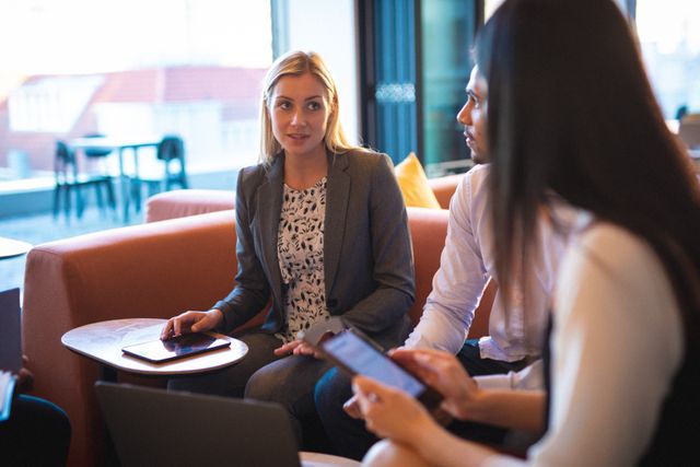 Caucasian businesswoman sitting and talking with diverse male and female colleague in office lounge. working in business at a modern office.
