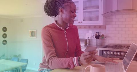 Young Woman Using Laptop and Credit Card in Modern Kitchen