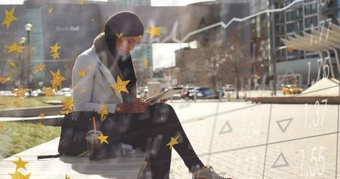 Muslim woman using tablet on city bench with financial charts and gold stars overlay