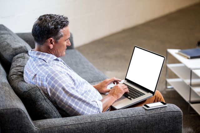 Profile view of businessman working with his laptop on a sofa