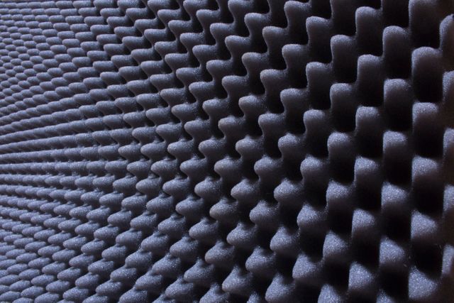 The image showcases a close-up view of an acoustic foam panel designed with an egg crate pattern. Perfect for illustrating concepts related to soundproofing, noise reduction, sound insulation, or audio engineering, the texture and details emphasize the panel's practicality in recording studios, theaters, or any sound-sensitive environments.
