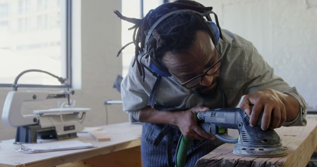 Focused woodworker using electric sander on wooden table - Download Free Stock Images Pikwizard.com