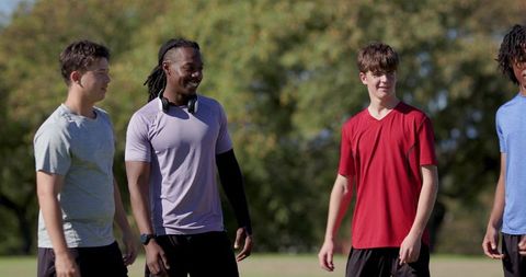 Young athletes chatting and laughing on sunny outdoor sports field