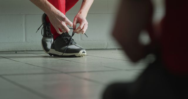 Lowsection of caucasian male hockey player tying his shoes in locker room. Sport, fitness, health and outdoor activities, unaltered.