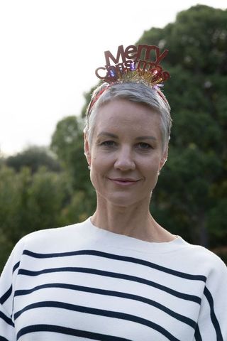 Mature woman wearing merry christmas headband and breton stripe sweater in garden