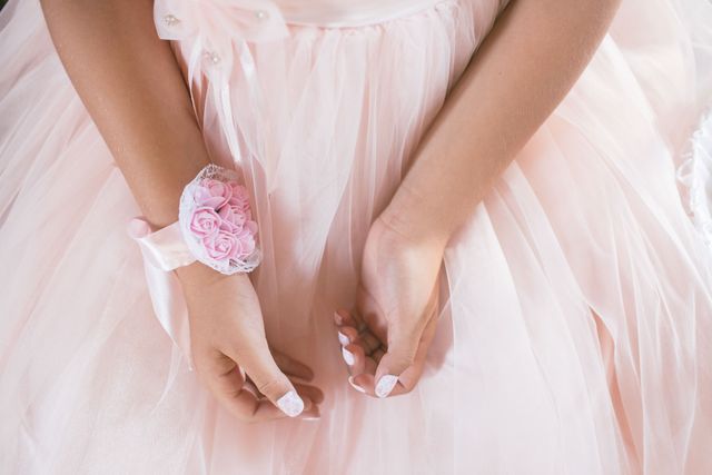 Young girl wearing a delicate pink dress with a floral wrist corsage, perfect for celebrating special occasions such as weddings, first communion, or formal events. Highlights elegance, beauty, and youthful innocence. Ideal for promotional material related to children's fashion, special events, and celebrations.