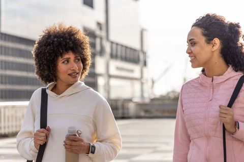 Post-workout women checking smartwatch with animated health stats while walking in city