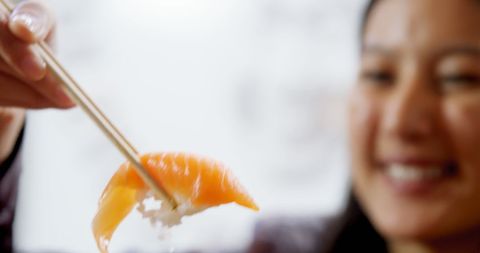 Joyful woman enjoys fresh sushi at japanese restaurant