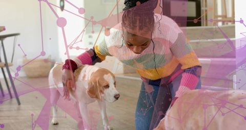 Kneeling woman petting two tan-white dogs in colorful striped sweater with network overlay