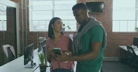 Coworkers discussing smartphone app in modern office