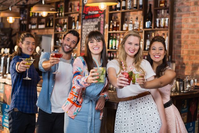 Portrait of smiling friends holding drinks in bar