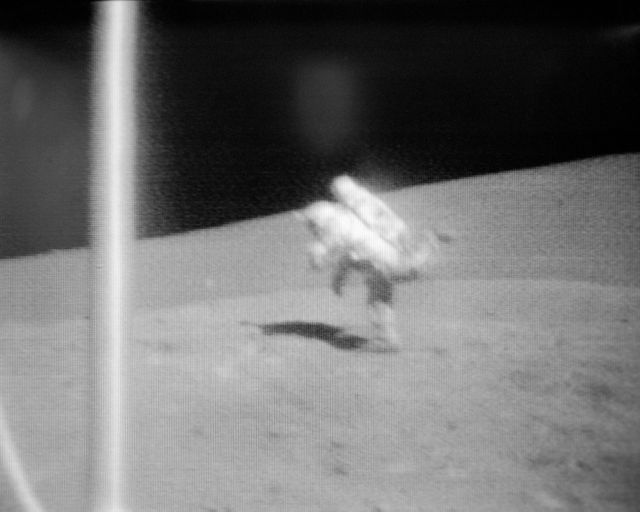This photograph shows an astronaut losing balance and falling during the second extravehicular activity of the Apollo 17 mission in 1972. Taken by an RCA TV camera on the Lunar Roving Vehicle, this image captures the historical moment on the moon's surface at the Taurus-Littrow landing site. Ideal for use in articles about space exploration history, NASA missions, or educational materials about the Apollo space program.
