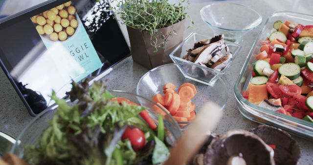 Fresh vegetables and ingredients with a tablet displaying a recipe on kitchen counter. Perfect for illustrating healthy eating, promoting cooking tutorials, food blogs, nutrition articles, and meal preparation guides.