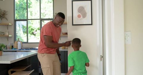 African american father bonding with son in bright kitchen smiling and playful morning
