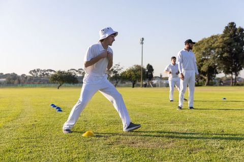 Cricket players warming up on sunlit field during team training session