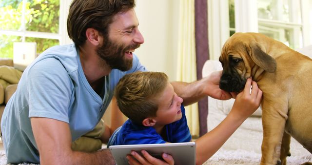 Father and son enjoy playful moment with their family dog in warm home environment. This image is great for family-oriented content, pet-friendly advertisements, and promoting healthy family relationships. Use to depict bonding, joy and domestic harmony in marketing materials or social media posts.