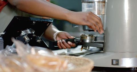African american barista locking portafilter on espresso machine at cafe counter