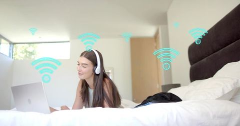Young woman relaxing on bed using laptop with headphones and Wi-Fi connectivity graphics