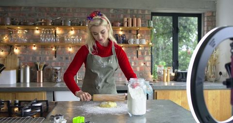 Home baker streaming holiday baking tutorial rolling dough in cozy rustic kitchen