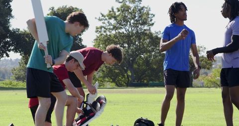 Multiracial teammates unpacking cricket gear and taking selfie in sunny park