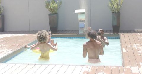 Friends enjoying plunge pool on private wooden deck with fountain and planters