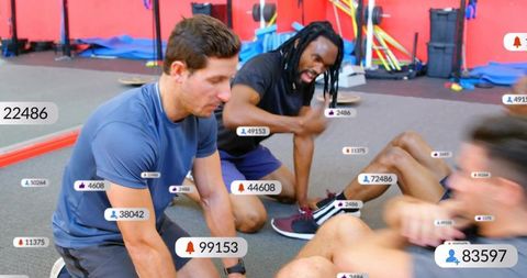Trainers anchoring feet cueing clients doing fast crunches with rep counters