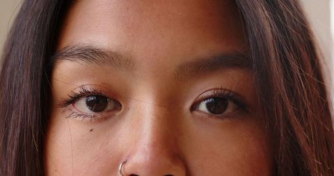 Closeup of chinese woman gazing with nose ring and subtle eyeliner in soft natural light