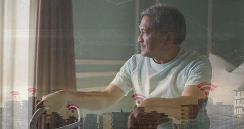 Senior man holding walker at bedside gazing out window with city wifi smart home concept