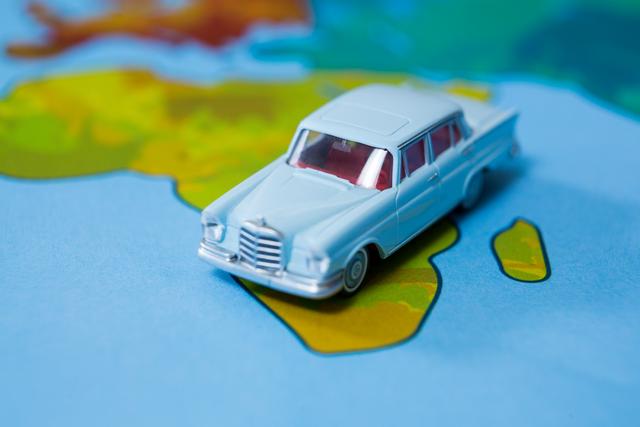 Miniature car placed on a world map, symbolizing travel, adventure, and exploration. Ideal for use in travel blogs, vacation planning websites, educational materials about geography, and advertisements for travel agencies.