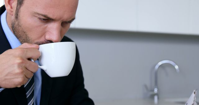 Businessman enjoying morning coffee in modern office, creating a productive atmosphere. Perfect for illustrating professional environments, morning routines, focus, and workplace habits.