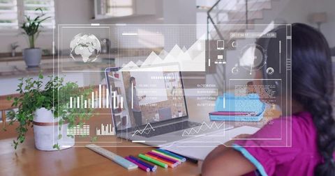 Studying schoolgirl using laptop with virtual data overlays at home desk remote learning