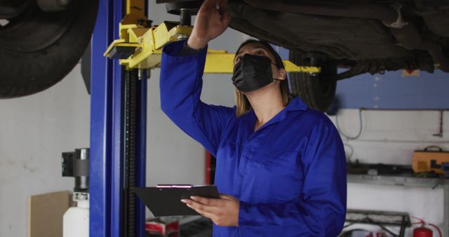 Female mechanic inspecting car undercarriage at auto repair shop - Download Free Stock Images Pikwizard.com