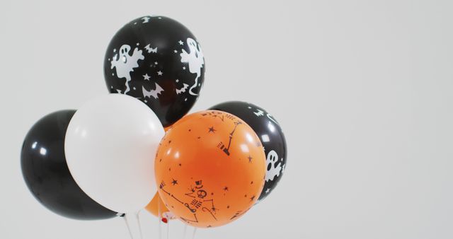 Ghost and skeleton printed bunch of halloween balloons against grey background. halloween holiday and celebration concept