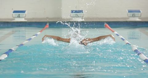 Competitive swimmer practicing butterfly stroke in pool water