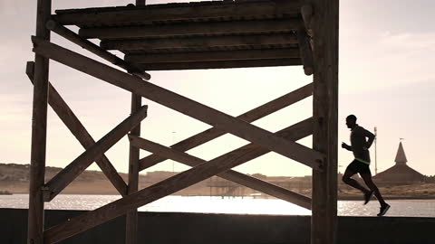 Silhouette of Runner by Beach in Afternoon Sunlight