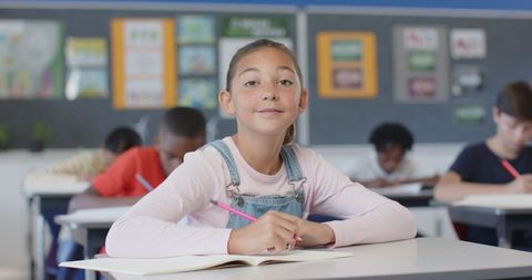 Schoolgirl in Class Looking Pensive While Writing Notes