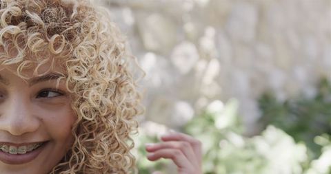 Joyful Young Woman with Curly Hair Smiling in Outdoor Setting