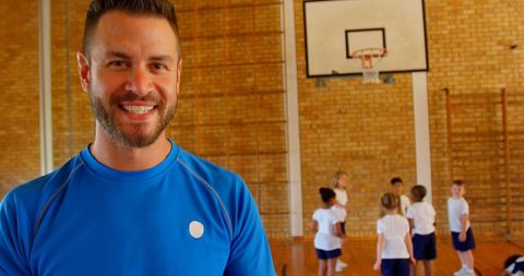 Smiling Coach Overseeing Kids Playing in School Gym